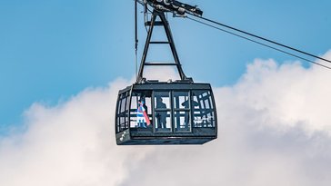 Eine der beiden neuen Carvatech-Pendelbahnkabinen der Tegelbergbahn in Anthrazit vor weißen Wolken